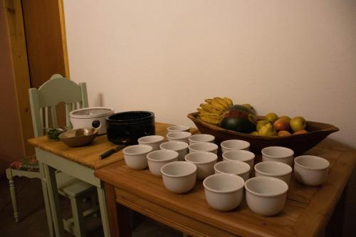a bunch of cups on a table with a bowl of fruit at POUSADA TONS DA MANTIQUEIRA in Piranguçu