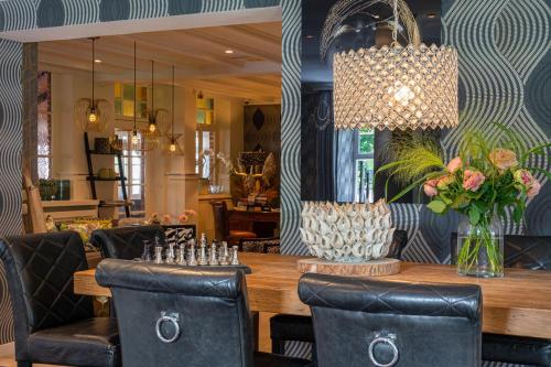 a dining room with a table and chairs and a chandelier at Boutique Hotel Slenaker Vallei - Buitengewoongenieten in Slenaken