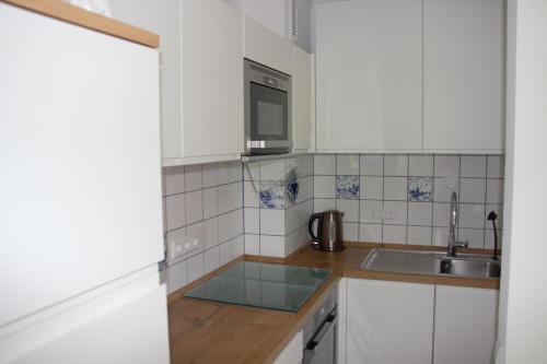 a kitchen with white cabinets and a sink at FeWo Moin - Horumersiel in Horumersiel