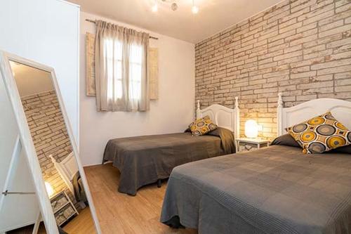a bedroom with two beds and a brick wall at Casa Jimena in Vejer de la Frontera