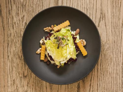 a black plate with food on a wooden table at Hotel Alpina in Vals