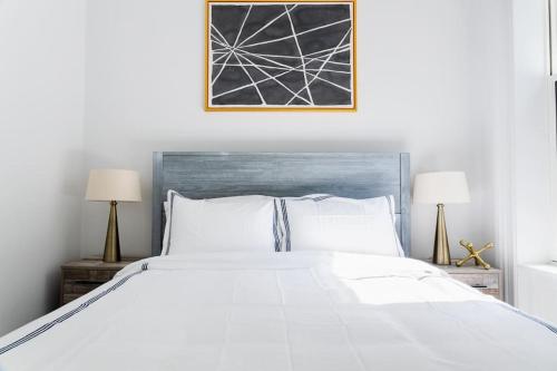 una camera da letto con un grande letto bianco con due lampade di E10-2 Designer East Village Townhouse 1BR W D a New York