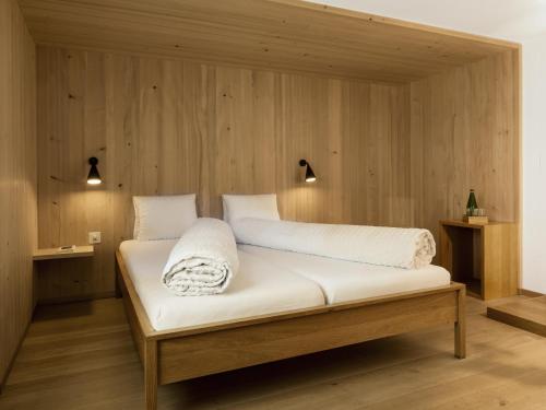 Bett in einem Zimmer mit Holzwänden in der Unterkunft Hotel Alpina in Vals
