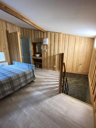 1 dormitorio con 1 cama y paredes de madera en Gîte : La vieille bâtisse., en La Baume-Cornillane