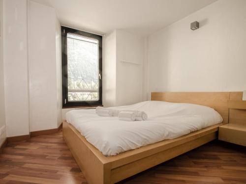 une chambre avec un lit avec des draps blancs et une fenêtre dans l'établissement Bel appartement central à Chamonix avec balcon et WiFi - FR-1-343-165, à Chamonix-Mont-Blanc