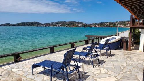 a group of chairs sitting on a patio next to the water at Vila Bela-Emília in Búzios