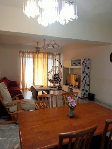 uma sala de estar com uma mesa de madeira e cadeiras em D'Mentari - Cozy 3 Rooms Apartment em Porto Dickson