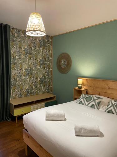 a bedroom with a large white bed and a chandelier at Lilas, Dahlia, Palme Bleue in Saint-Aignan
