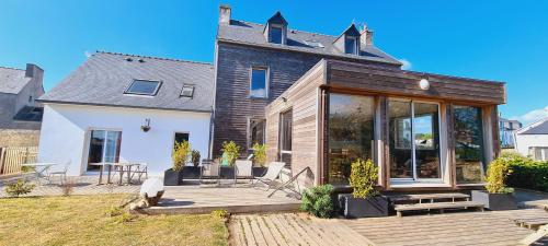 une maison avec une terrasse en bois devant elle dans l'établissement Gîtes Neige d'écume, à Lampaul