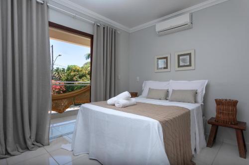 a white bedroom with a bed and a window at Casa de Praia Maragogi in Maragogi
