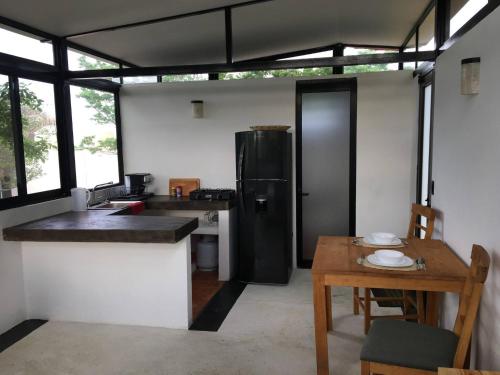 eine Küche mit einem schwarzen Kühlschrank und einem Tisch in der Unterkunft Bungalow Doble Con Vista parcial al Mar, Cocina Completa in Cuatunalco