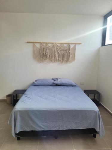 een slaapkamer met een bed met een blauwe deken en 2 tafels bij Habitación en Iker's House in Mérida
