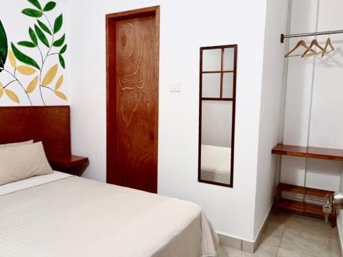 a bedroom with a white bed and a mirror at Piccolo Bed & Breakfast in Tarapoto