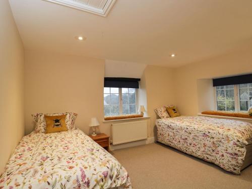 a bedroom with two beds and two windows at Beech Cottage in Stroud