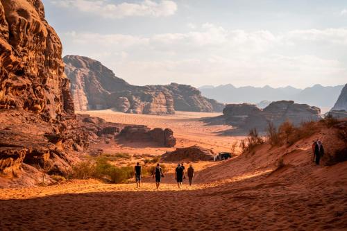 Un groupe de personnes marchant sur un chemin de terre dans le désert dans l'établissement Wadi rum secrets camp, à Wadi Rum