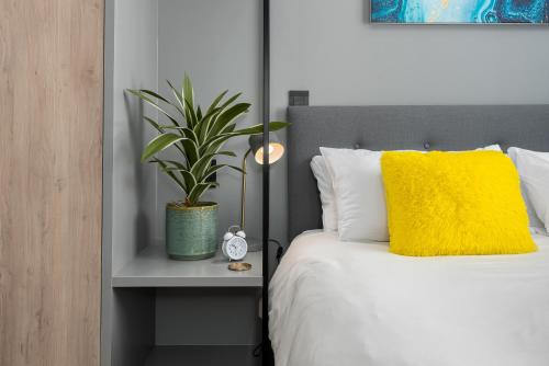 a bedroom with a bed with a yellow pillow and a plant at One Thibault Luxury Apartments in Cape Town