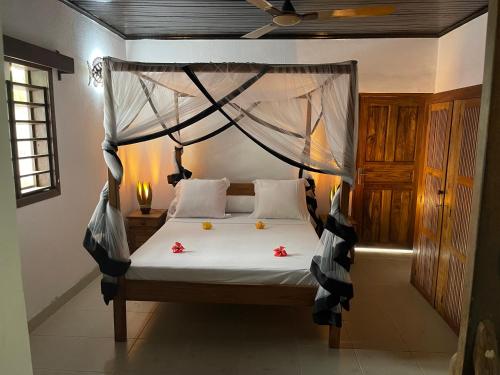 a bedroom with a canopy bed with flowers on it at maison vanilianadia in Nosy Be