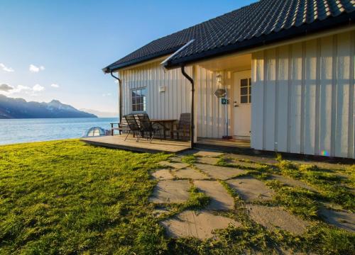 a cottage by the water with a stone walkway at Lyngen North in Rotsund