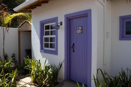 een paarse deur aan de zijkant van een huis bij POUSADA TONS DA MANTIQUEIRA in Piranguçu