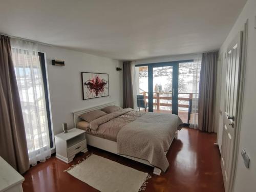 a bedroom with a bed and a balcony with windows at Mountain Home Bran in Bran