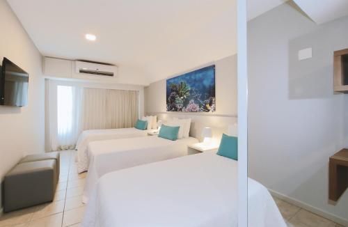 a hotel room with two beds and a tv at Hotel Ponta Verde Maceió in Maceió