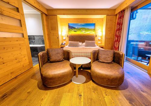 a bedroom with a bed and two chairs and a table at Nendaz 4 Vallées & SPA 4* Superior in Nendaz