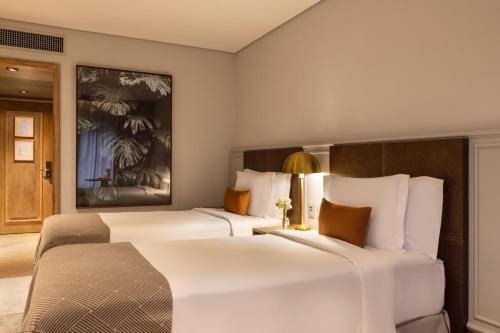 two beds in a hotel room with white sheets at L'Hotel PortoBay São Paulo in Sao Paulo