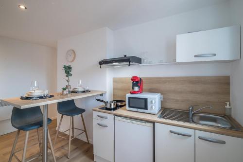 une cuisine avec un four micro-ondes et un comptoir avec des tabourets dans l'établissement L’Usine - Tarbes Centre, à Tarbes