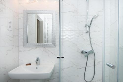 a bathroom with a sink and a shower with a mirror at WaterFront City Apartments by UrbanRent in Budapest
