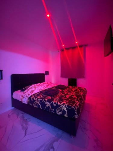 Suite cinéma et jacuzzi privé في مولان: غرفة نوم مع سرير مع أضواء وردية عليه