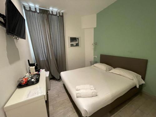 a bedroom with a bed with white sheets and a television at Relais Merulana Guest House in Rome