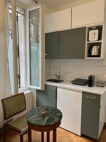 une petite cuisine avec une table et une table sidx sidx sidx sidx dans l'établissement Studio de Charme de Verneuil, à Paris