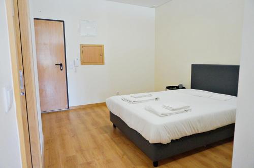 Cette chambre comprend un lit avec des draps blancs et du parquet. dans l'établissement Tomás Flat, à Porto