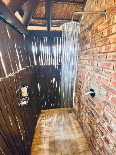 a bathroom with a brick wall and a shower at Charihandra Game Lodge in Addo