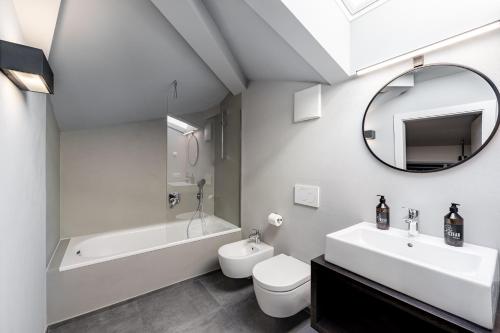 uma casa de banho com um lavatório, um WC, uma banheira e um espelho. em Stay COOPER l CITY LOFT em Bolzano