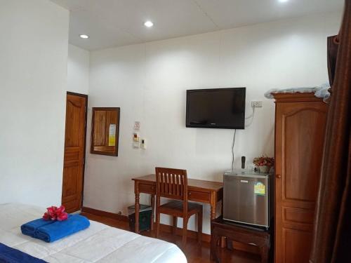 a bedroom with a bed and a desk and a tv on the wall at Tara Raft in Kanchanaburi