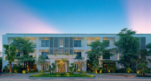 a large white building with trees in front of it at Eightfold Urban Resort in Siem Reap