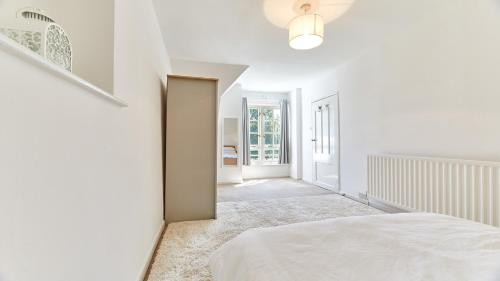 a white bedroom with a bed and a hallway at The Pink House in Durham