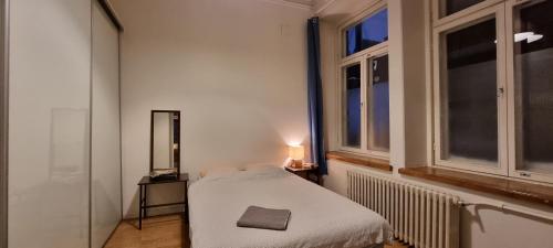 a white room with a bed and a mirror and windows at 4 Blocks From Stockmann in Helsinki