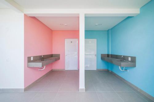 baño con 2 lavabos y paredes de color rosa y azul en Vila do Centro Bombinhas, en Bombinhas