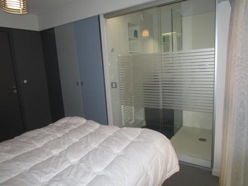 レ・サ​​ーブル・ドロンヌにあるAppartement Les Sables-d'Olonne, 2 pièces, 4 personnes - FR-1-197-367の白いベッドとガラスの壁が備わるベッドルーム1室が備わります。