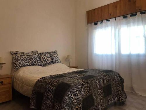 Un dormitorio con una cama con una manta de leopardo y una ventana en Casa alquiler 5 per. Santa Teresita 4 cuadras Mar en Santa Teresita