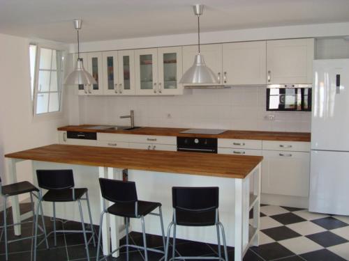 une cuisine avec des placards blancs et un comptoir avec des tabourets de bar dans l'établissement Maison 4 pièces avec WiFi à 800m de la plage - Saint-Georges-d'Oléron - FR-1-246A-75, à Chaucre