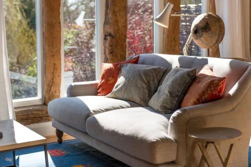 a living room with a couch with pillows on it at Deepwell Granary is a lovely thatched barn with attached meadow woodland in Buxhall