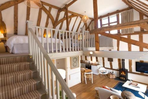 um quarto no sótão com uma escada e um quarto em Deepwell Granary is a lovely thatched barn with attached meadow woodland em Buxhall