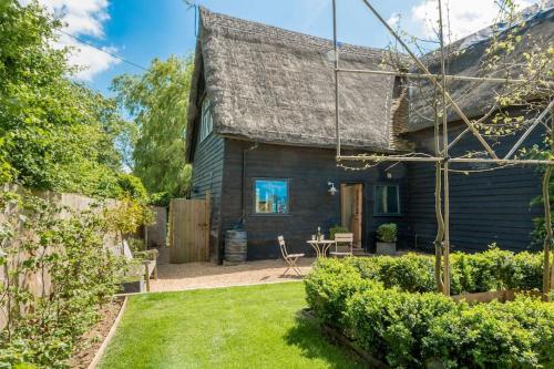 a wooden house with a garden and a yard at Deepwell Granary is a lovely thatched barn with attached meadow woodland in Buxhall