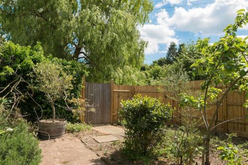 a backyard with a wooden fence and trees at Deepwell Granary is a lovely thatched barn with attached meadow woodland in Buxhall