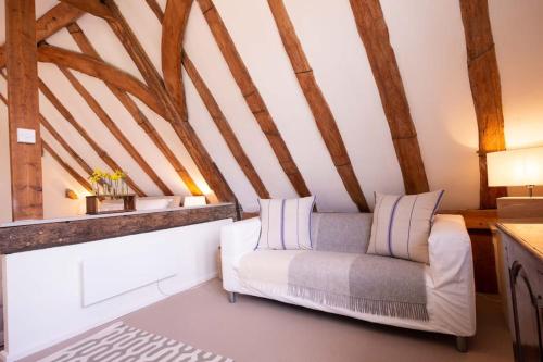 a living room with a white couch and wooden beams at Deepwell Granary is a lovely thatched barn with attached meadow woodland in Buxhall