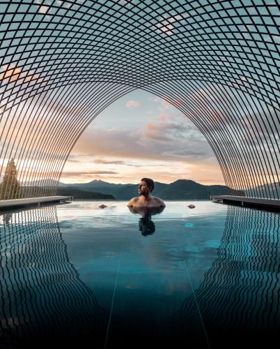 a man sitting in a pool of water in a swimming pool at Gloriette Guesthouse Boutiquehotel in Soprabolzano