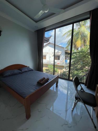 a bedroom with a bed and a chair and a large window at Moonshine Guesthouse in Siem Reap